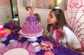 girl blowing out candles on a cake