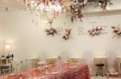 a room with a table and chairs on a bare wooden floor under a chandelier