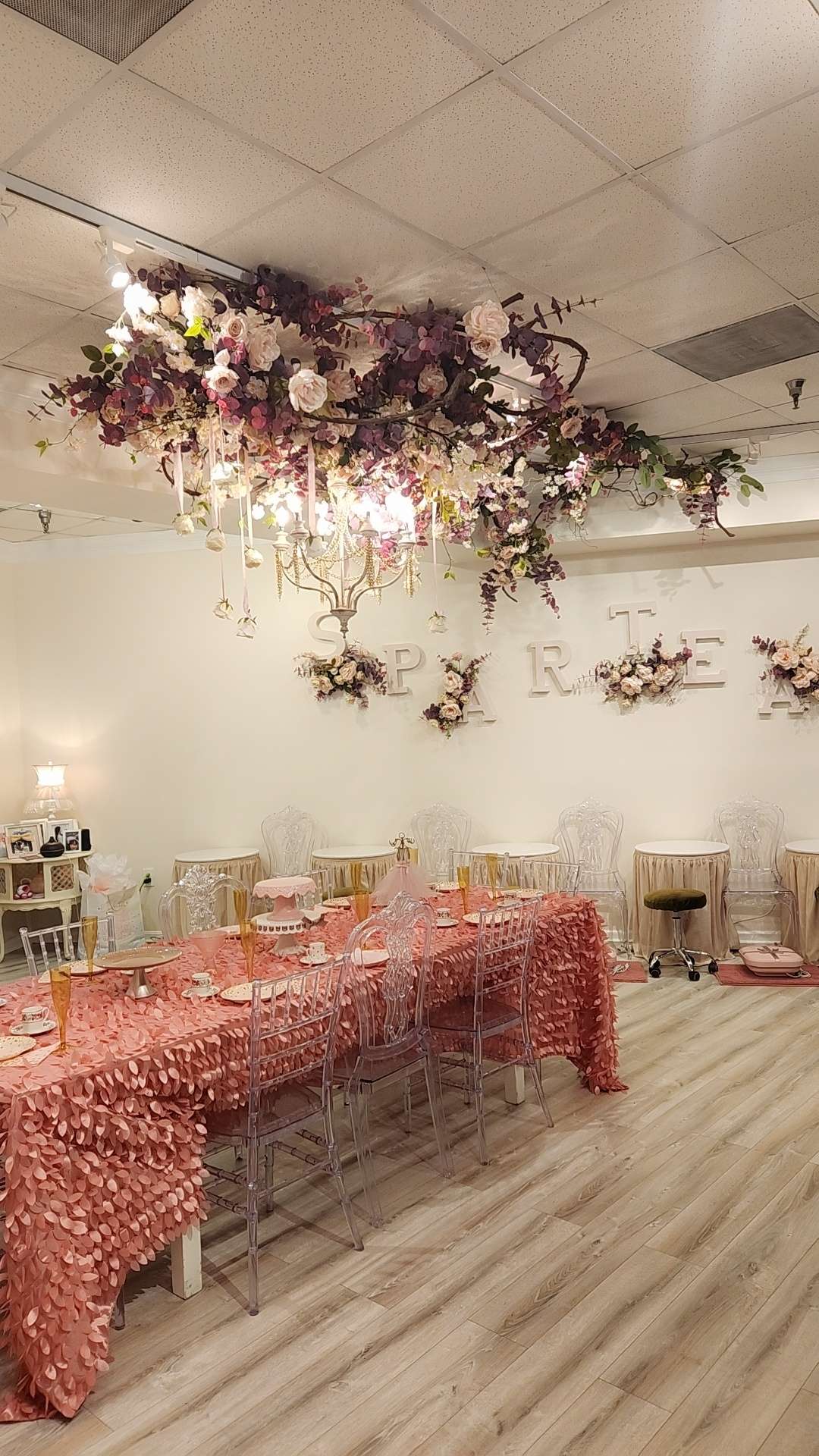 a room with a table and chairs on a bare wooden floor under a chandelier