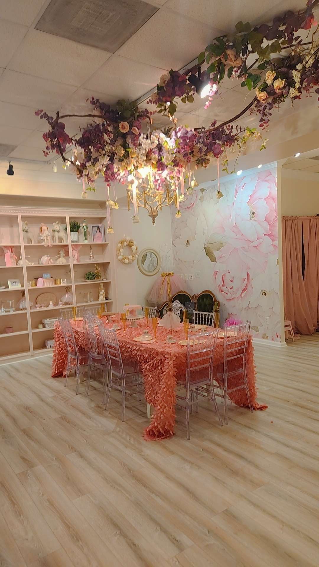 a room with a table and chairs on a bare wooden floor under a chandelier