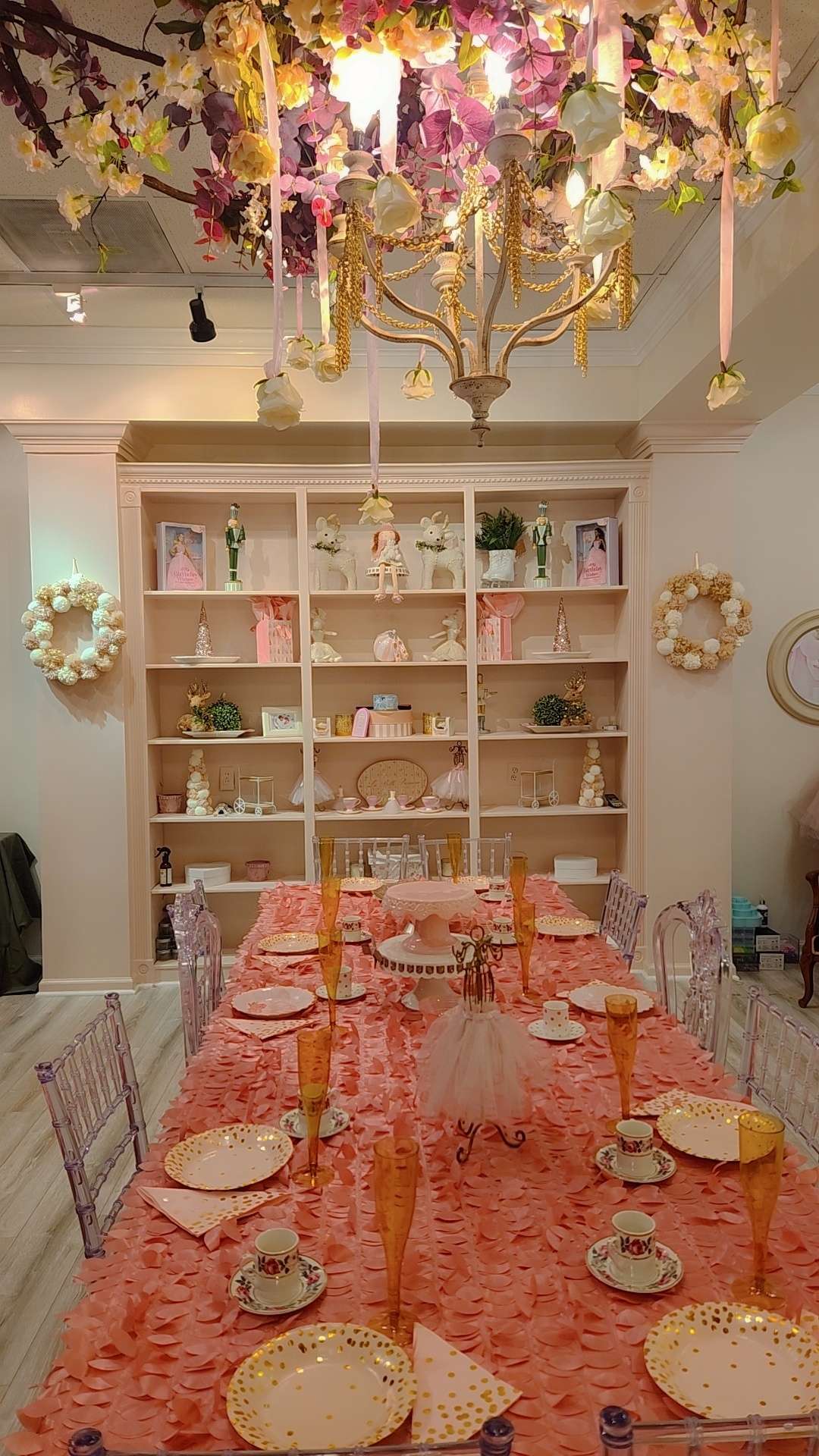 a room with a table and chairs on a bare wooden floor under a chandelier